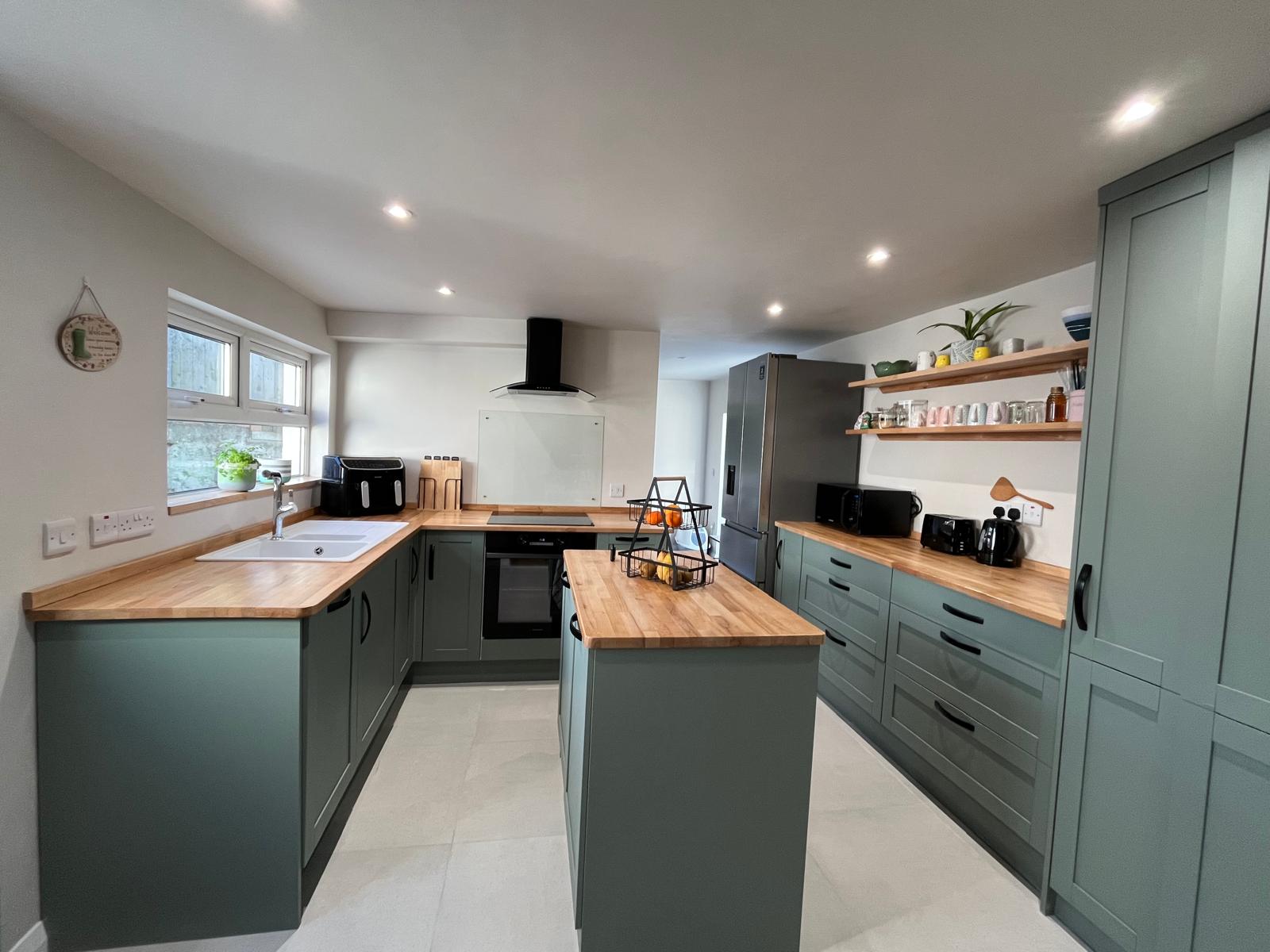Completed kitchen with island, open timber shelving and tiled floor