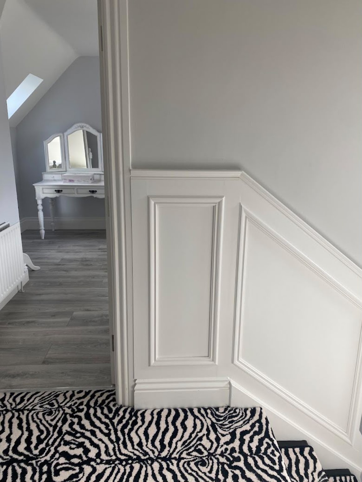 Painted wall panelling and skirting fitted on a landing and stairs