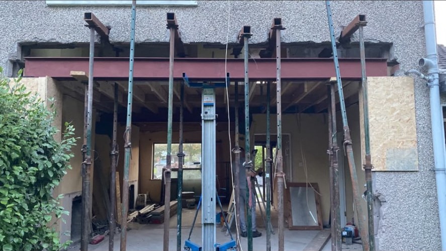 Structural steel beam installed on props while an opening is formed in a house